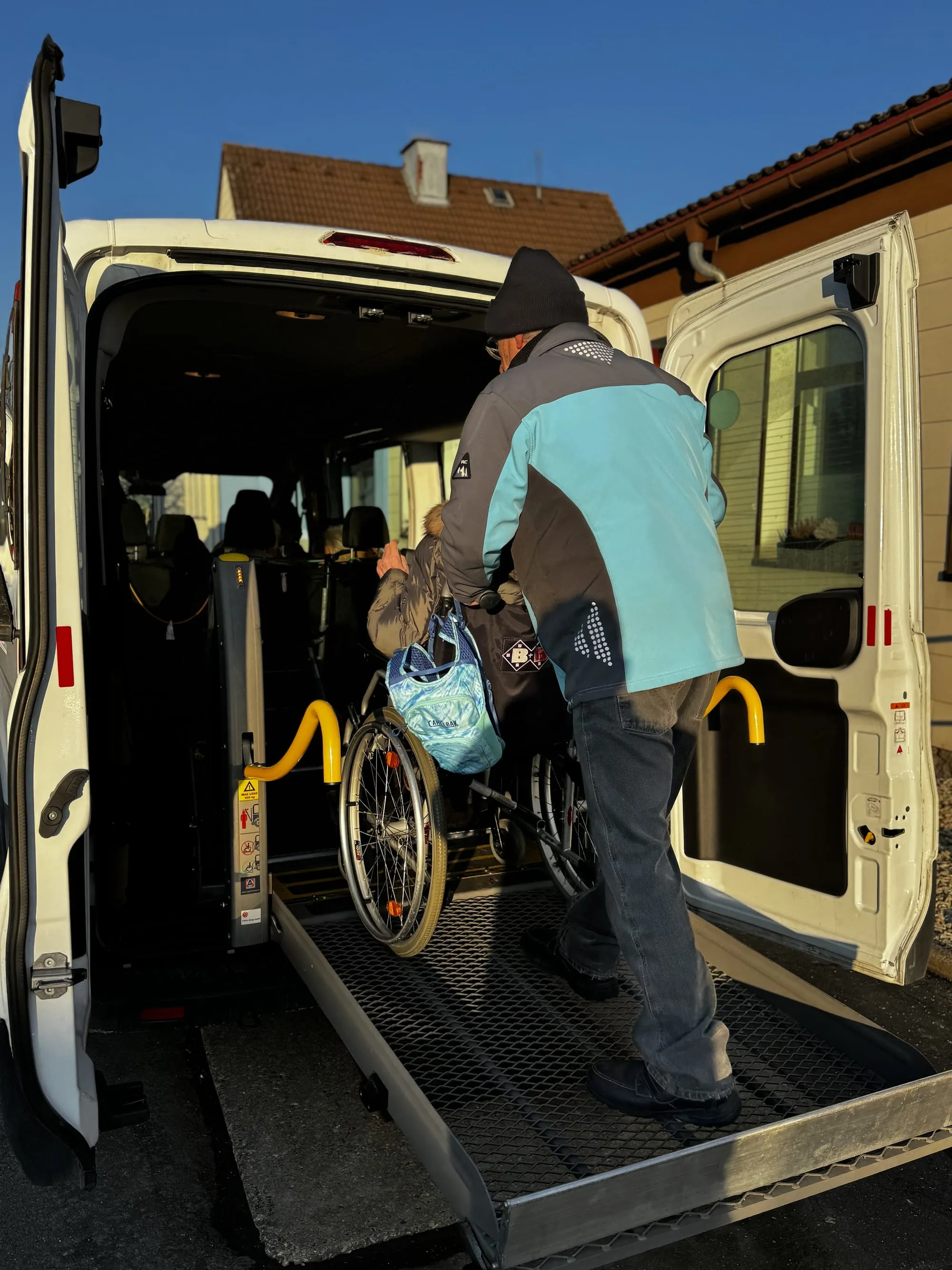 Ein Rollstuhl wird über die Rampe in den Kleinbus geschoben