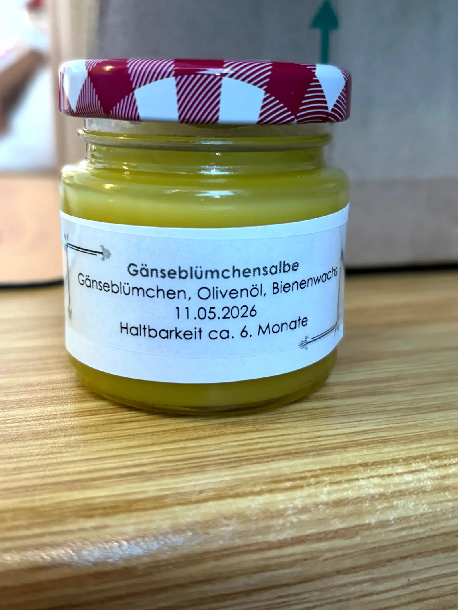 Selbst hergestellte Gänseblümchensalbe im Glas mit handgeschriebenem Etikett
