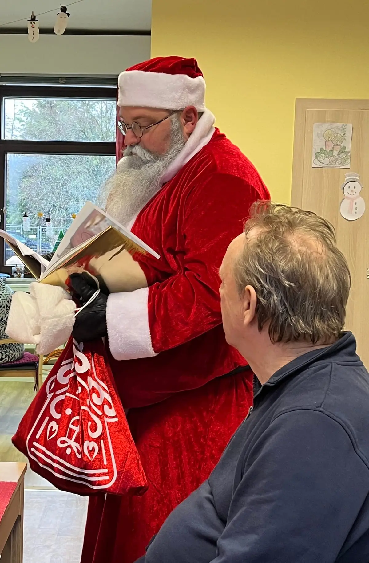 Der Nikolaus liest einem Gast aus seinem goldenen Buch vor