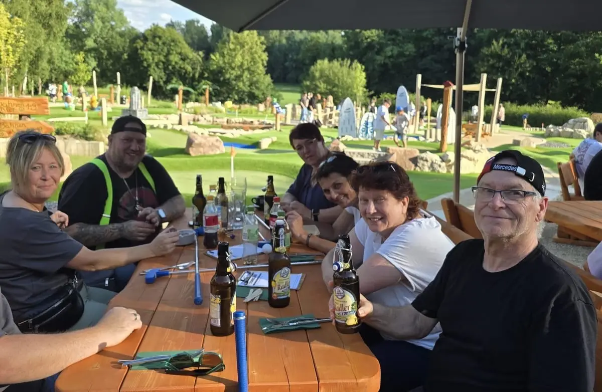Kolleginnen und Kollegen sitzen beim Teamausflug gut gelaunt am Tisch